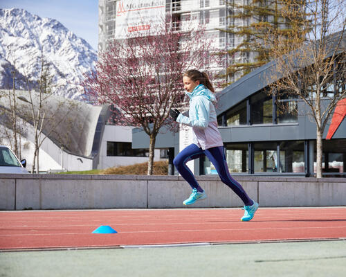 dziewczynka biegnąca po bieżni w zimowej kurtce biegowej i rękawiczkach do biegania