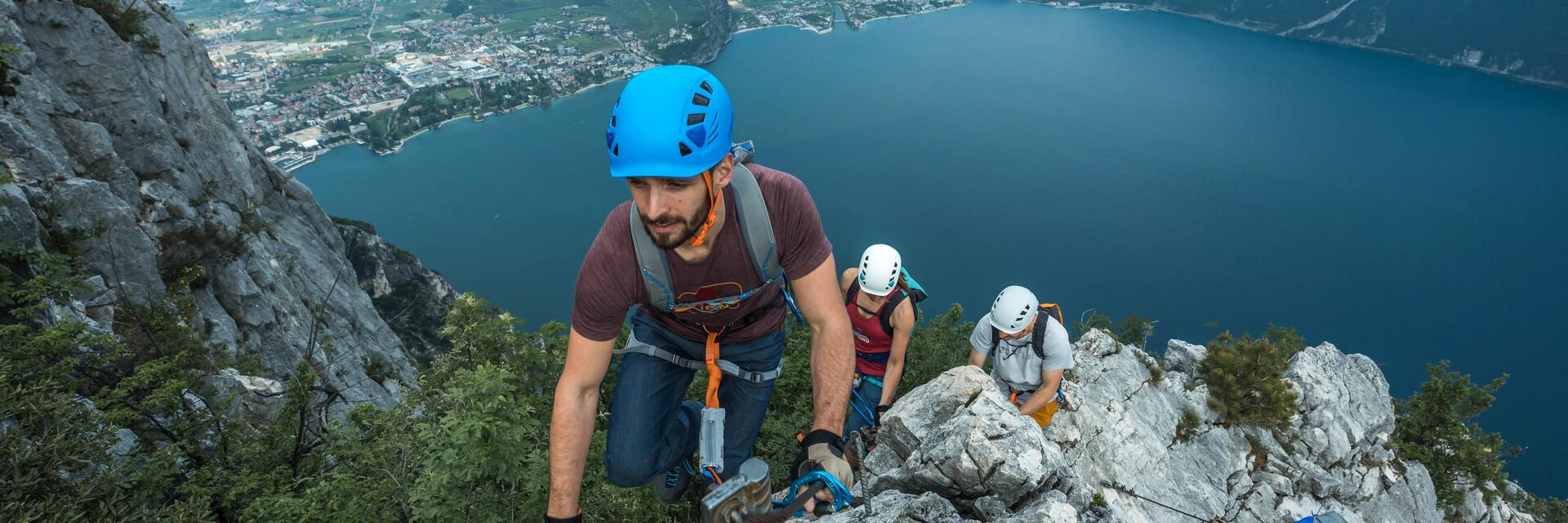 Mężczyźni i kobieta wspinający się po  górach w kaskach wspinaczkowych 