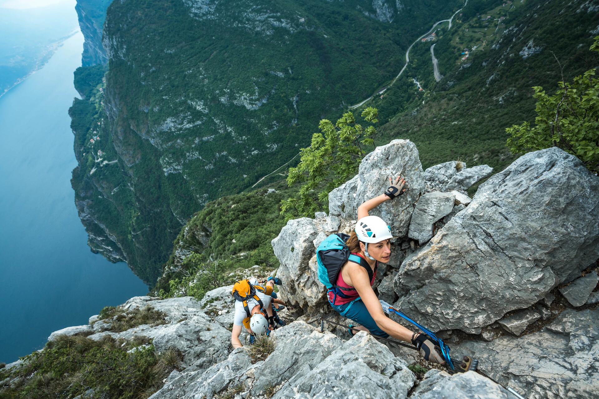 Kobieta i mężczyzna w kaskach wspinaczkowych uprawiający wspinaczkę górską z użyciem lin asekuracyjnych