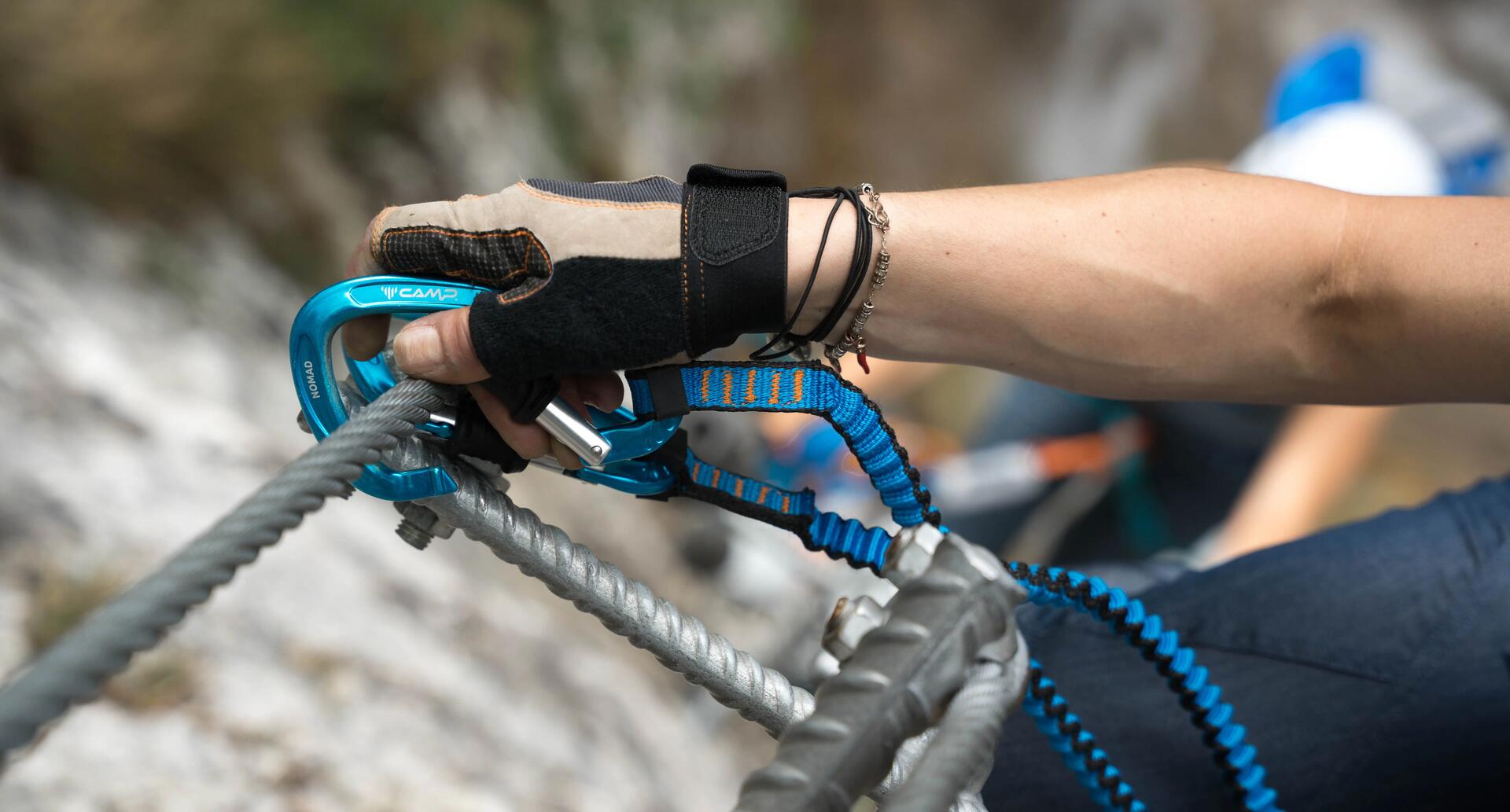 Turysta na szlaku vi ferrata z karabińczykiem w ręku