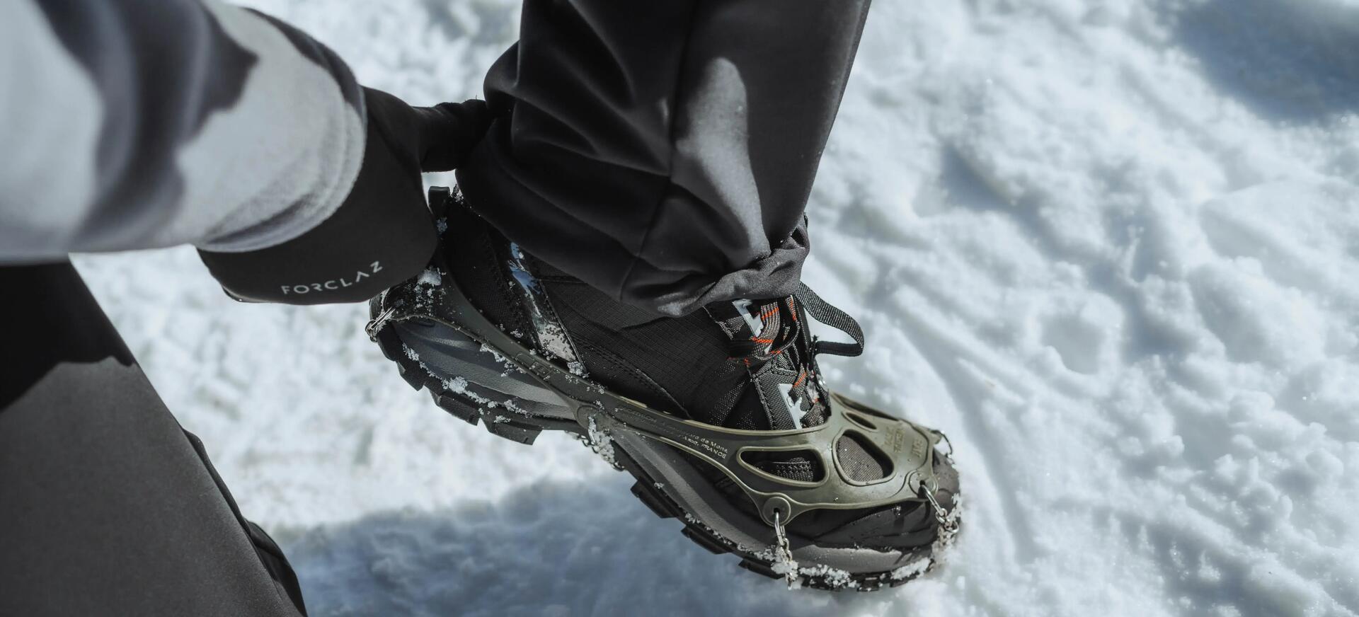 osoba nakładająca raczki na buty trekkingowe