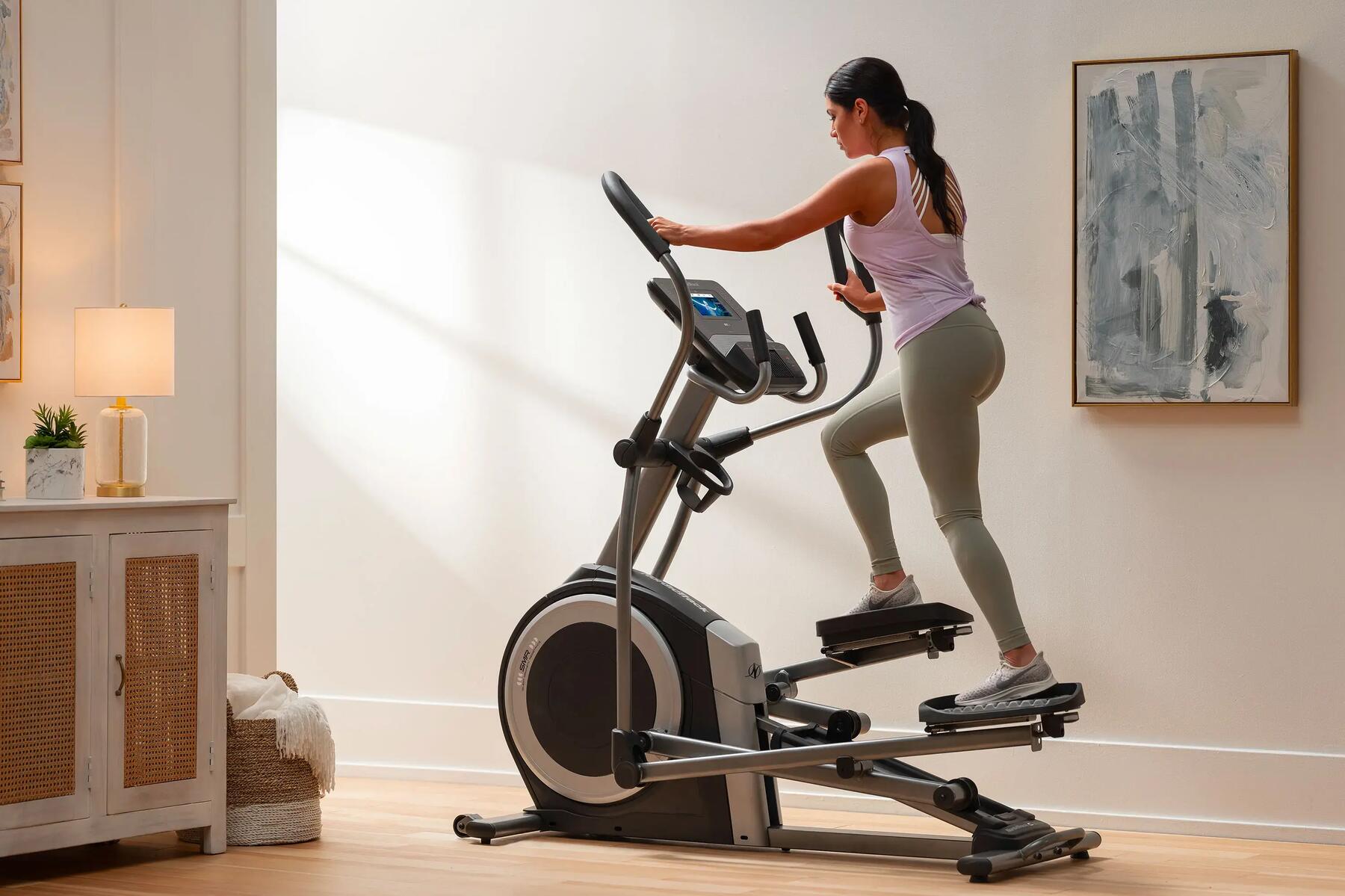 Kobieta w legginsach fitness trenująca na orbitreku w domu