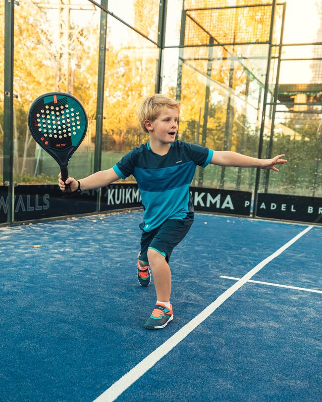 Junge im Padeloutfit holt auf der Grundlinie zum Schlag aus