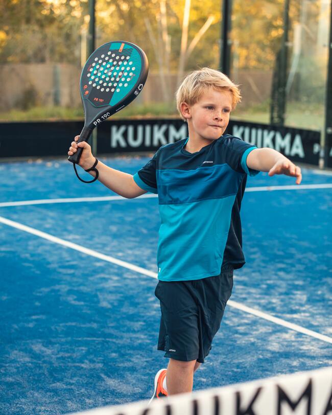 Junge im Padeloutfit holt zum Schmetterball aus