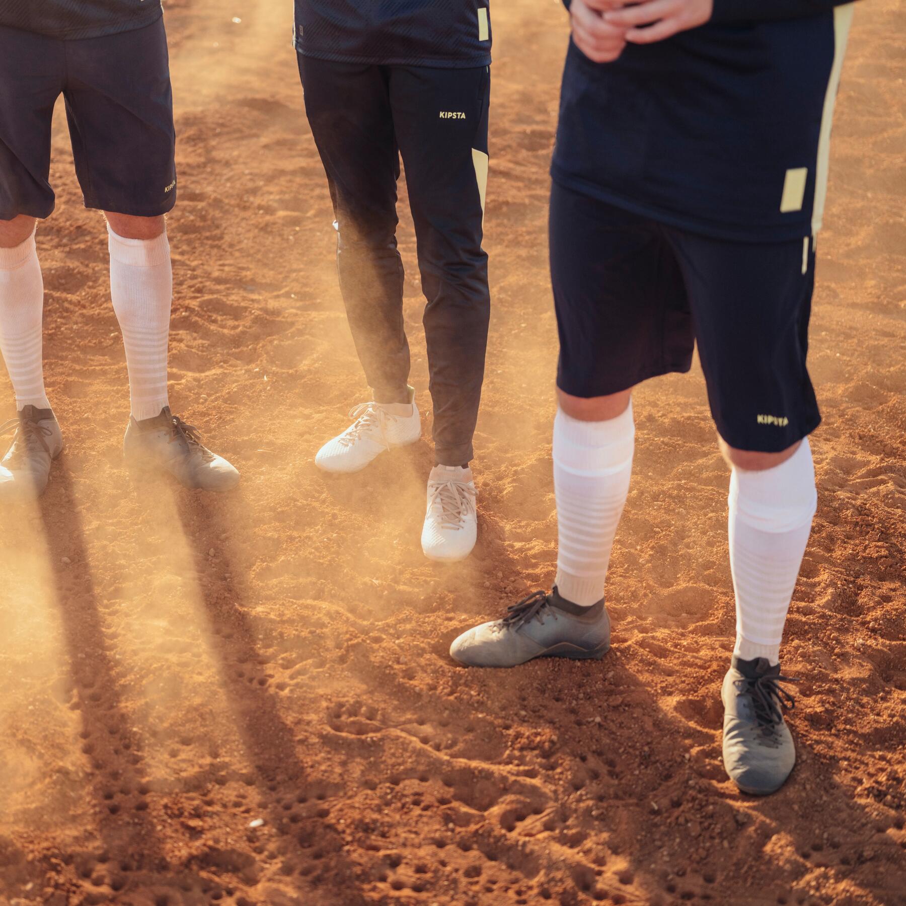 Piłkarze stojący na ceglastym podłożu w butach i odzieży piłkarskiej