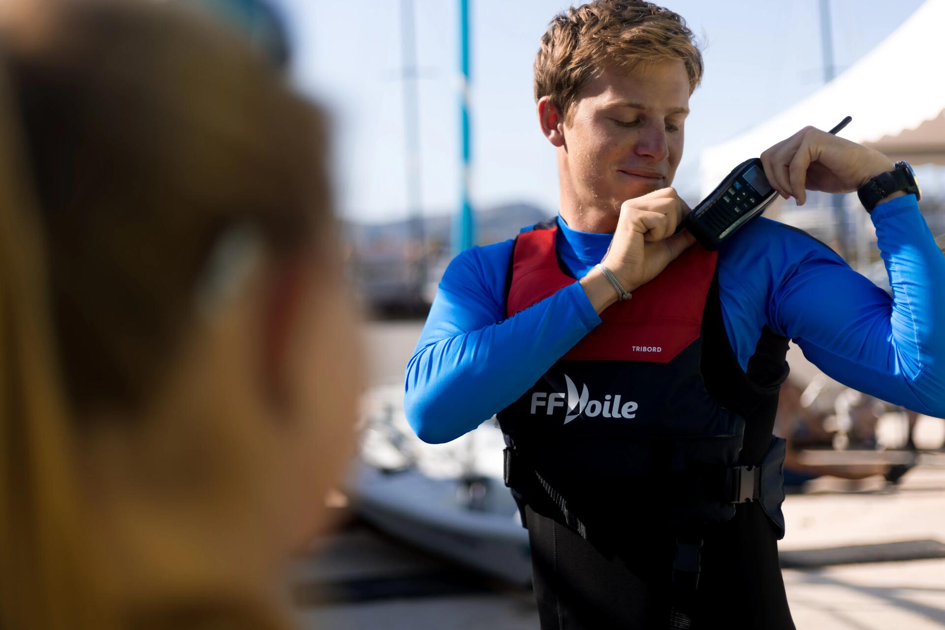 moniteur de voile fixant la BHF sur son gilet de flottaison