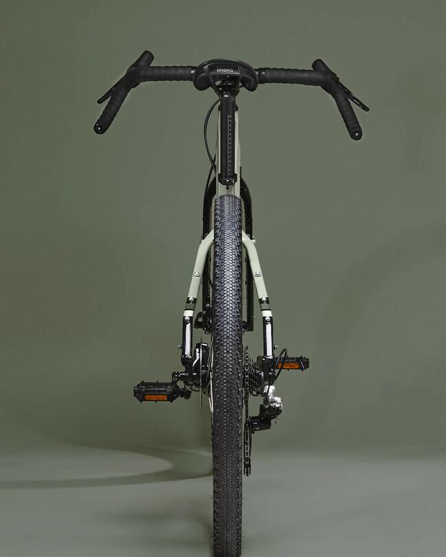 Grünes Fahrrad in Frontalansicht mit breitem schwarzem Rennradreifen; grüner Hintergrund