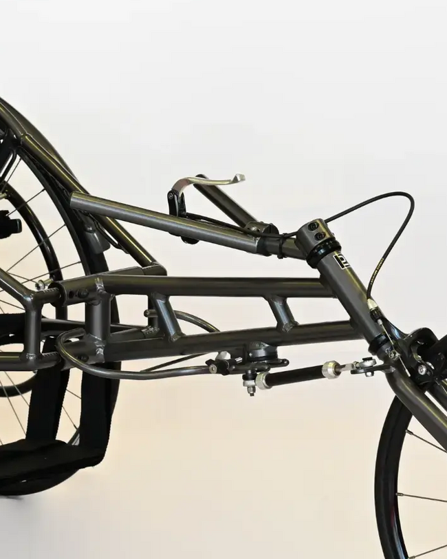 ATHLETICS WHEELCHAIR mit Dual-Lenksystem in Metallgrau, geschwungene Formen, glatte Textur, einstellbarer Lenkungsdämpfer.