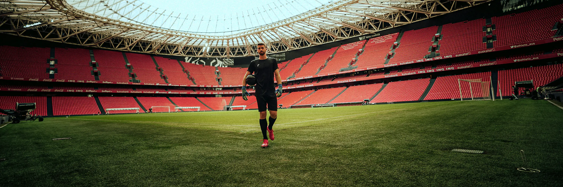 Piłkarz w odzieży piłkarskiej trzymający piłkę stojąc na stadionie
