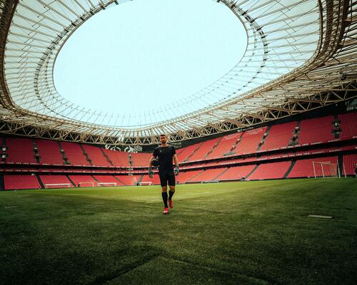 Piłkarz w odzieży piłkarskiej trzymający piłkę stojąc na stadionie