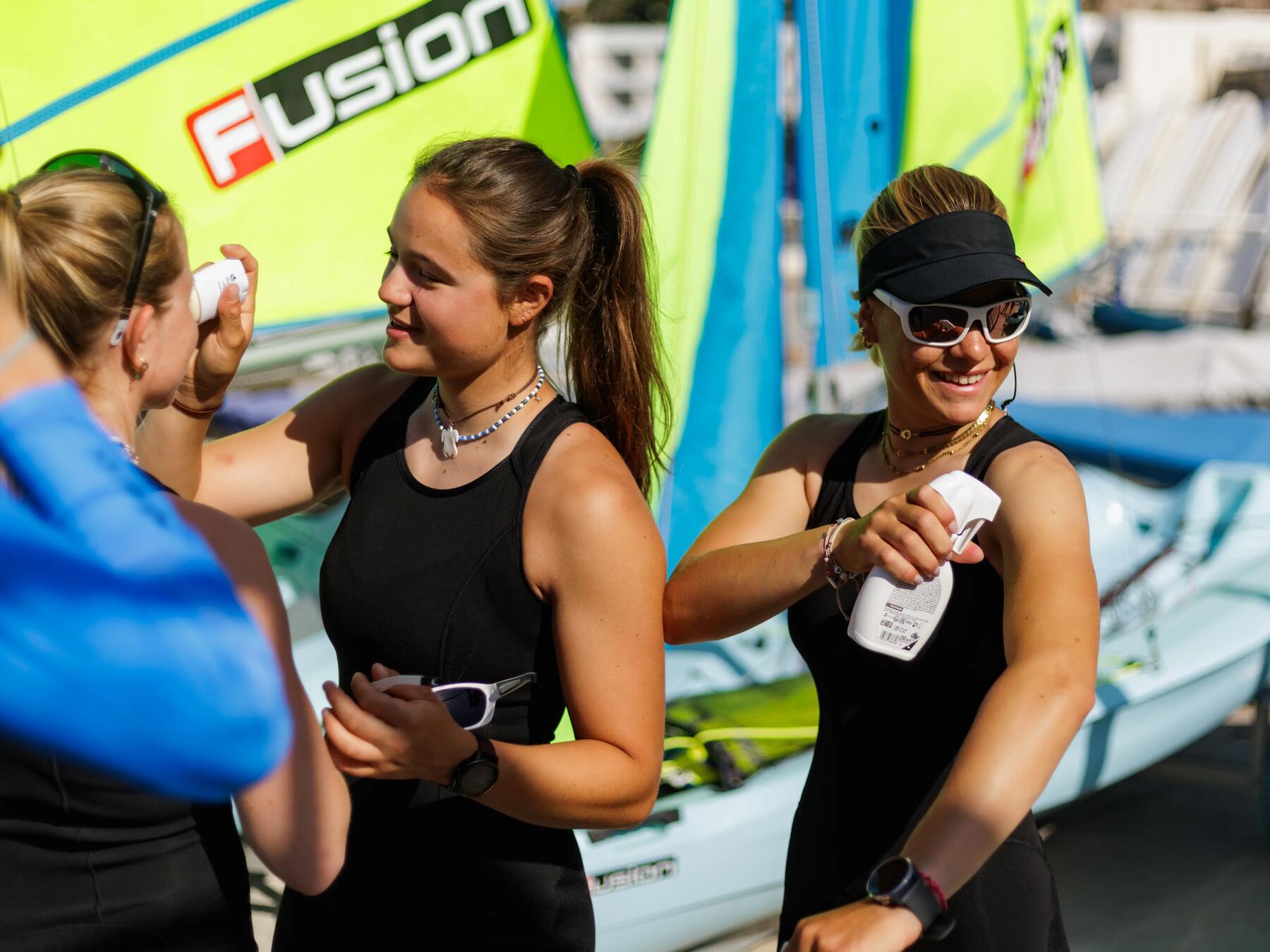 equipo de vela echándose protector solar