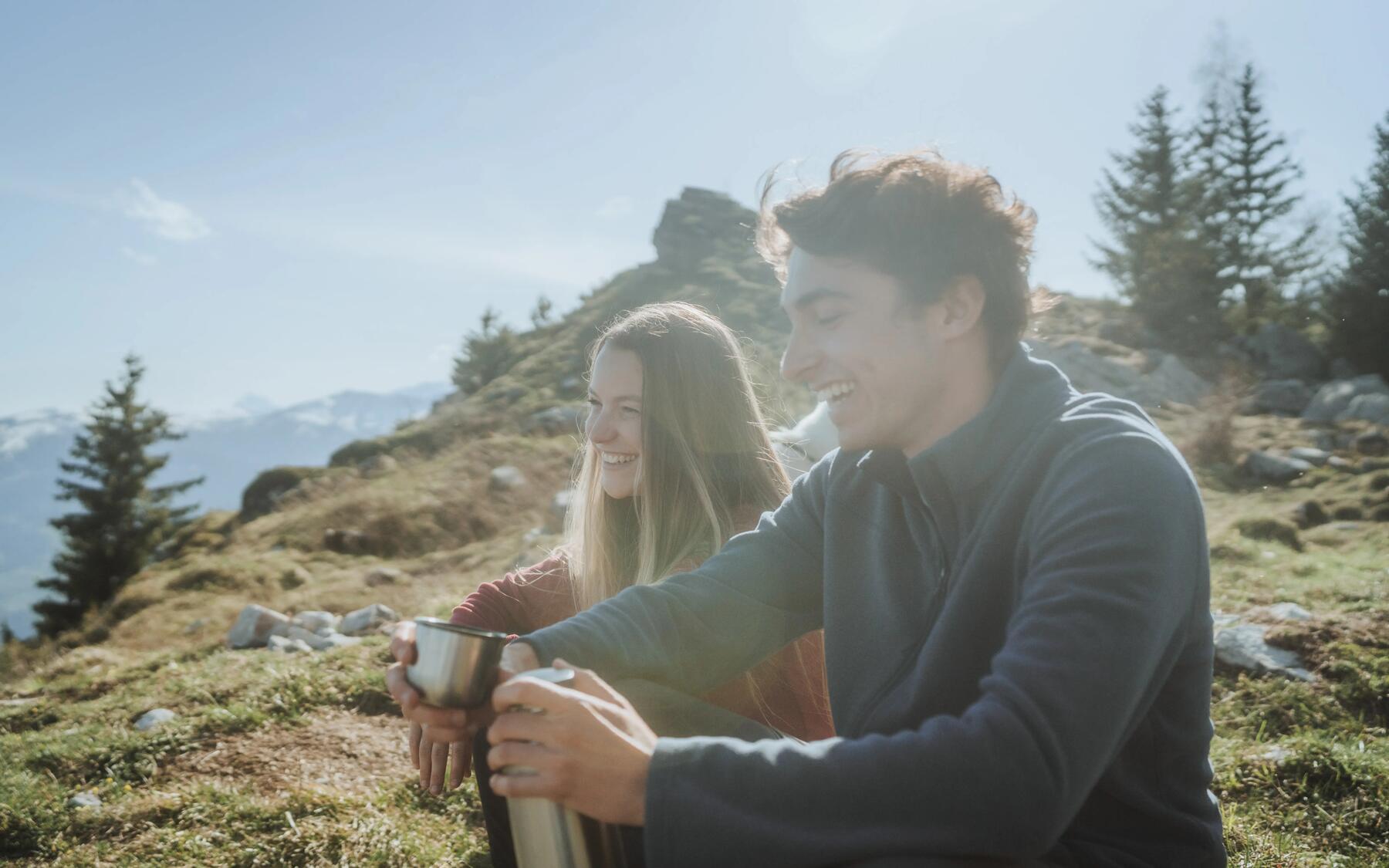 Young woman and man sitting on a mountain top