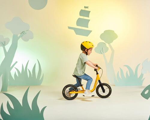 une draisienne jaune avec un enfant qui roule