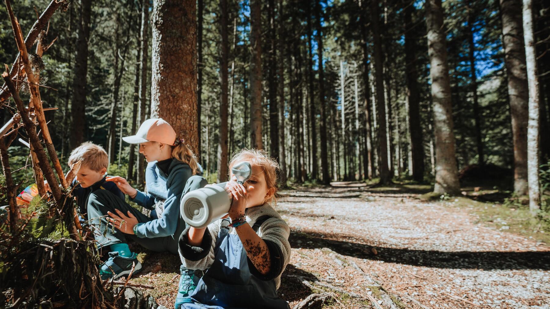 Enfant en randonnée qui regarde un tronc d'arbre et sa mousse