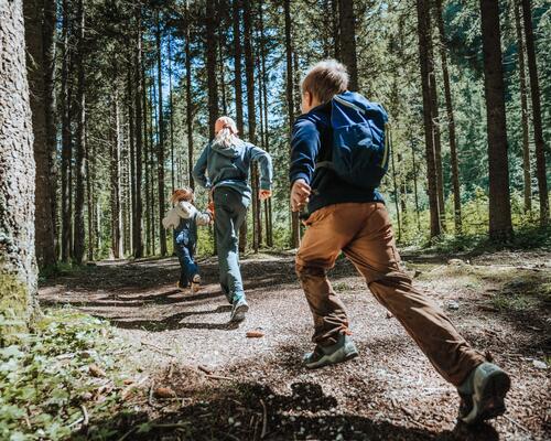 dzieci w odzieży trekkingowej biegnące przez las