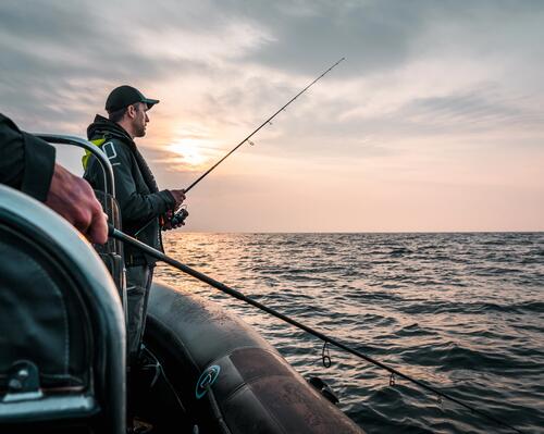 Angler steht auf einem Boot auf dem Meer mit der Angel in der Hand