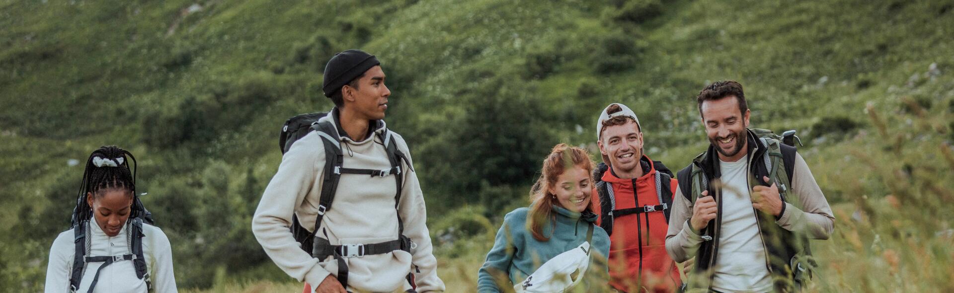 Grupa ludzi w trakcie trekkingu ubrana w polary z plecakami turystycznymi