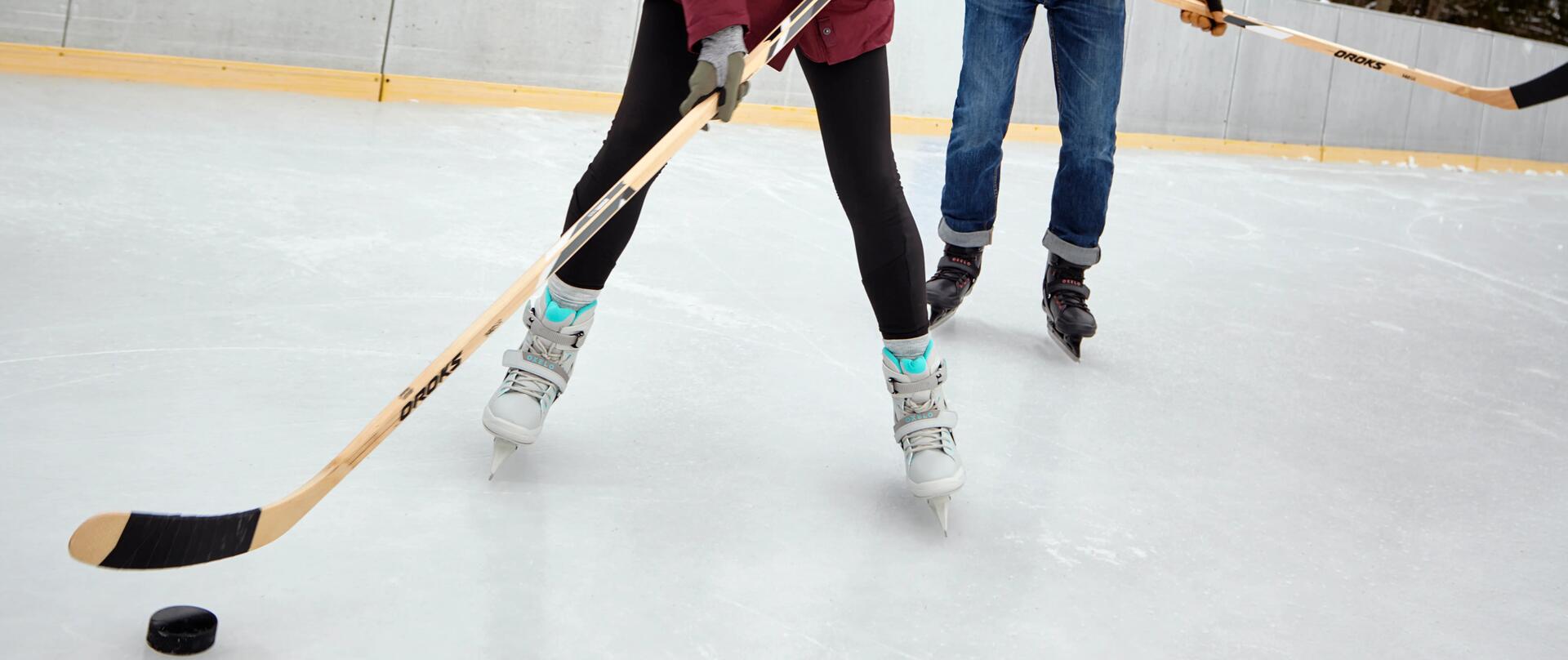 2 osoby na lodowisku grają w hokeja kijami hokejowymi