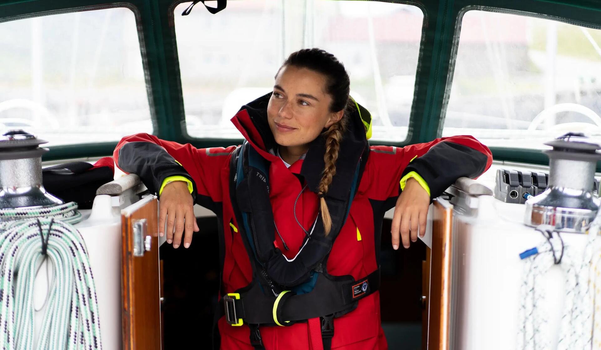 kobieta w kurtce żeglarskiej stojąca na pokładzie jachtu 