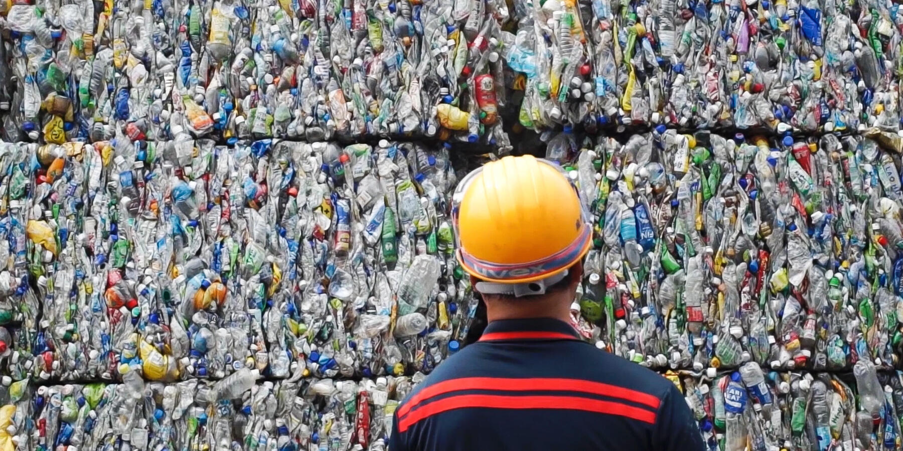 Photo d'un homme devant un tas de bouteilles plastiques