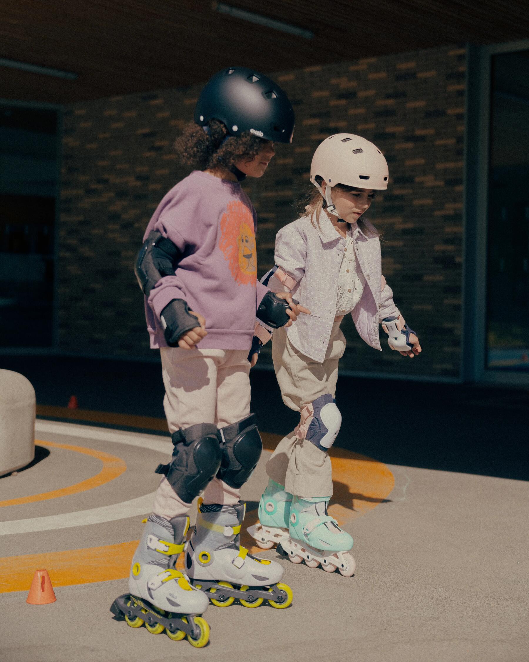 two young kids holding hands and roller skating together