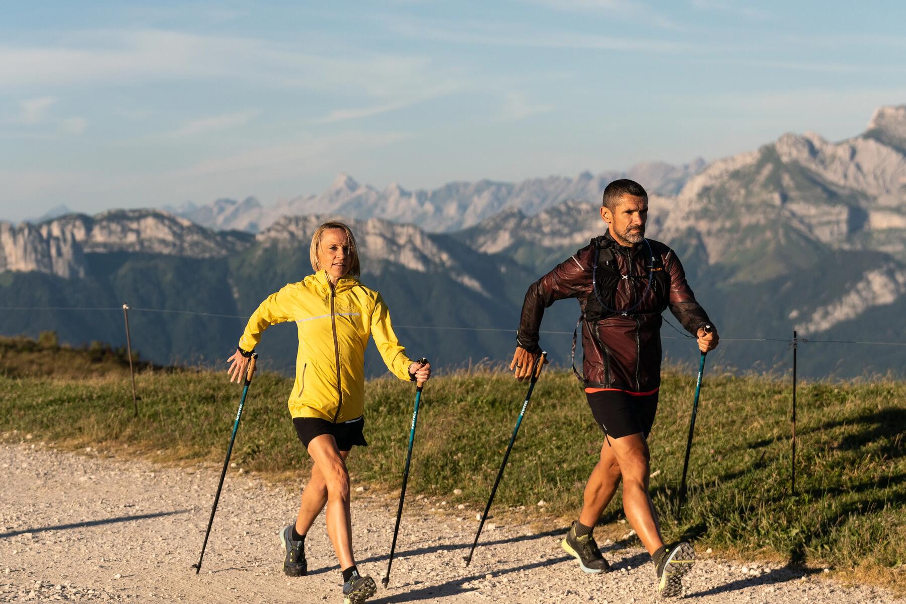 Para uprawiająca nordic walking na szlaku górskim z użyciem kijków