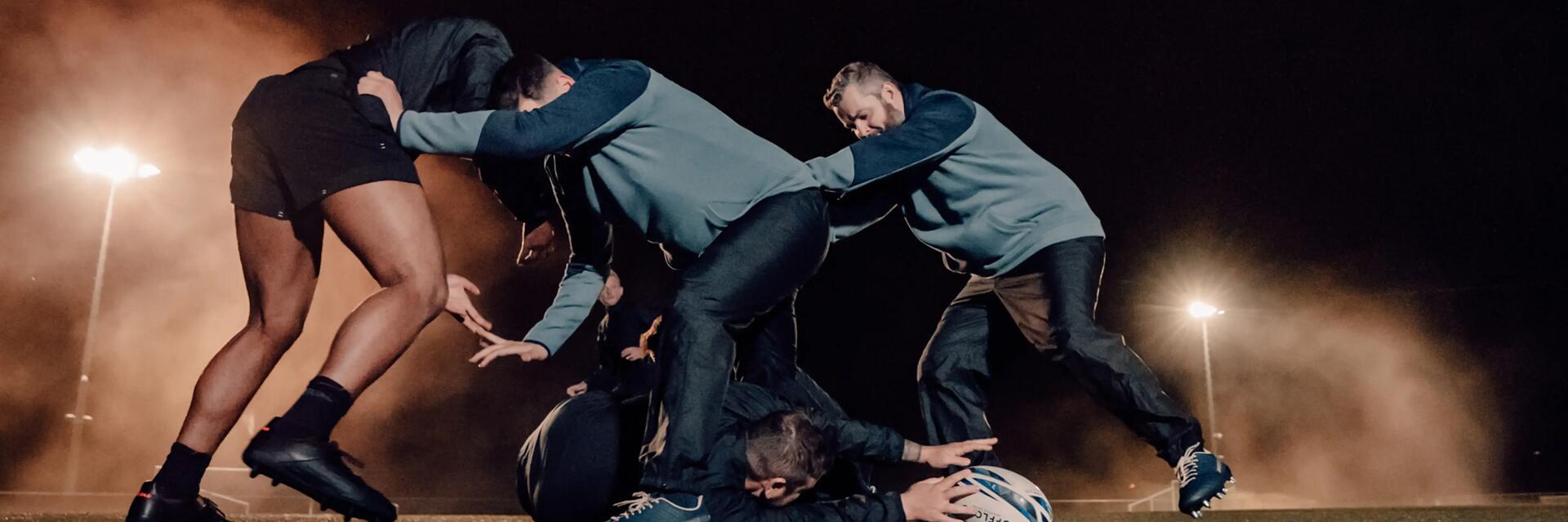 Mężczyźni w odzieży do rugby trenujący rugby na boisku 