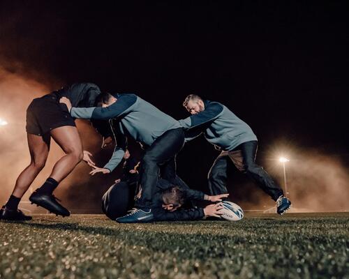 Mężczyźni w odzieży do rugby trenujący rugby na boisku