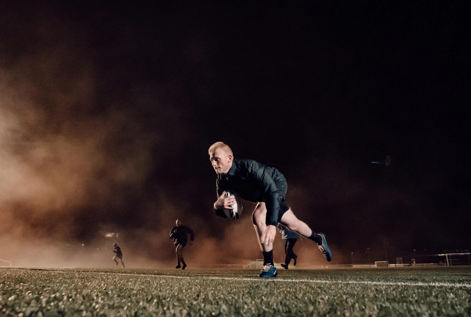 mężczyzna z piłką do rugby na boisku