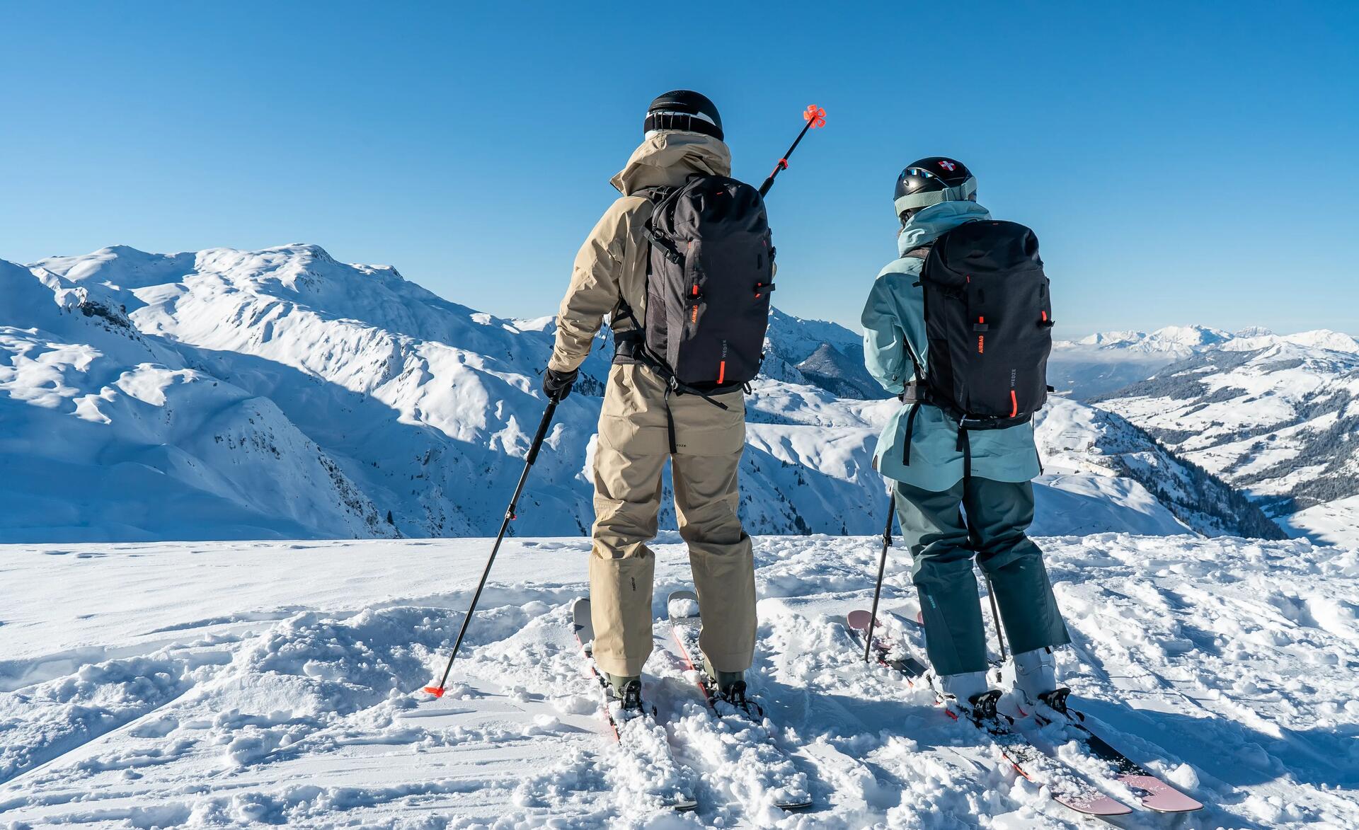 Two skiers looking down their mountain ski slope