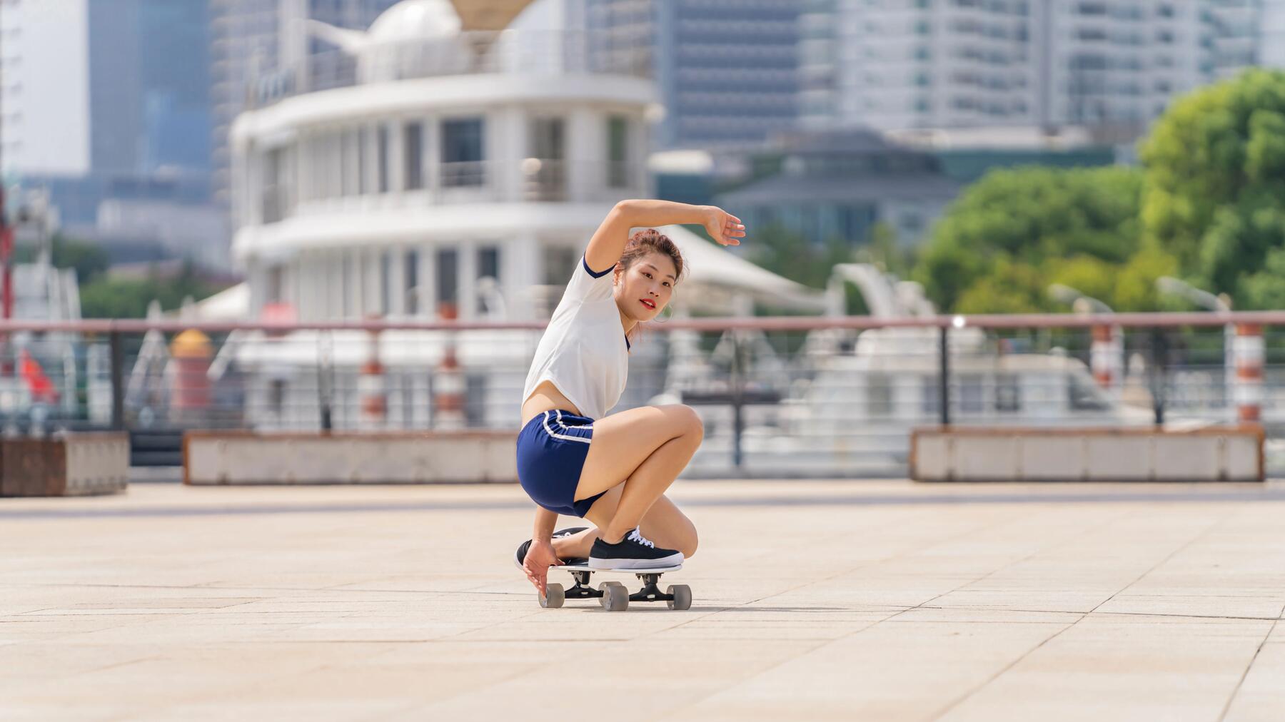 Dziewczyna w odzieży sportowej wykonująca trick na longboardzie