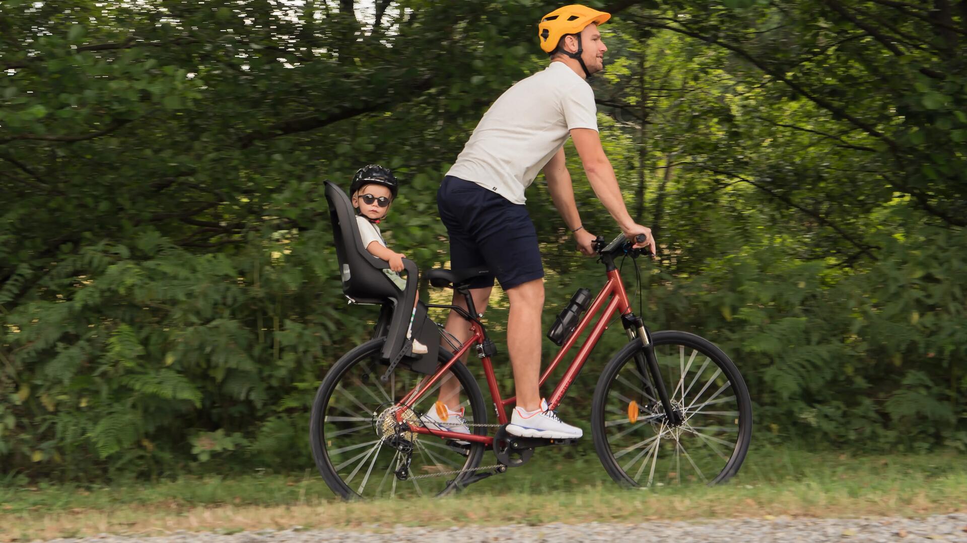 homem a pedalar com criança na cadeirinha
