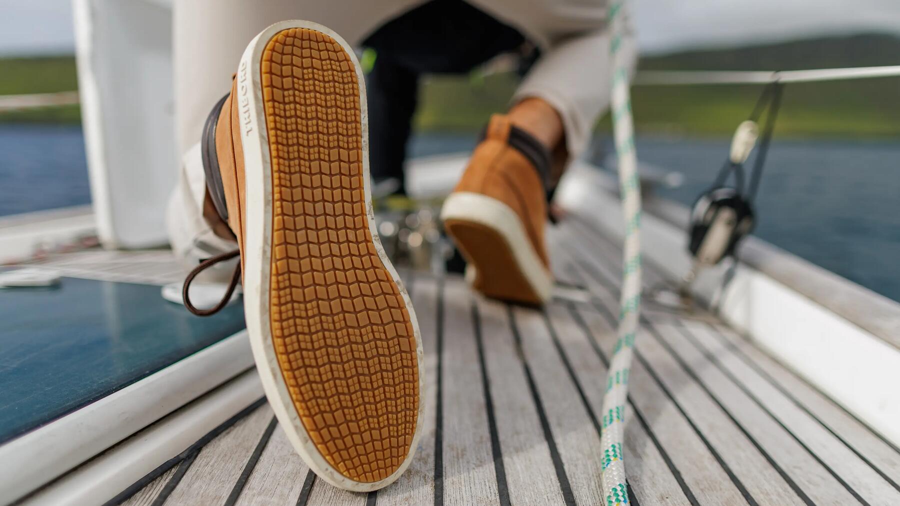 Mężczyzna ubrany w buty sportowe na żaglówkę wiążący supeł żeglarski