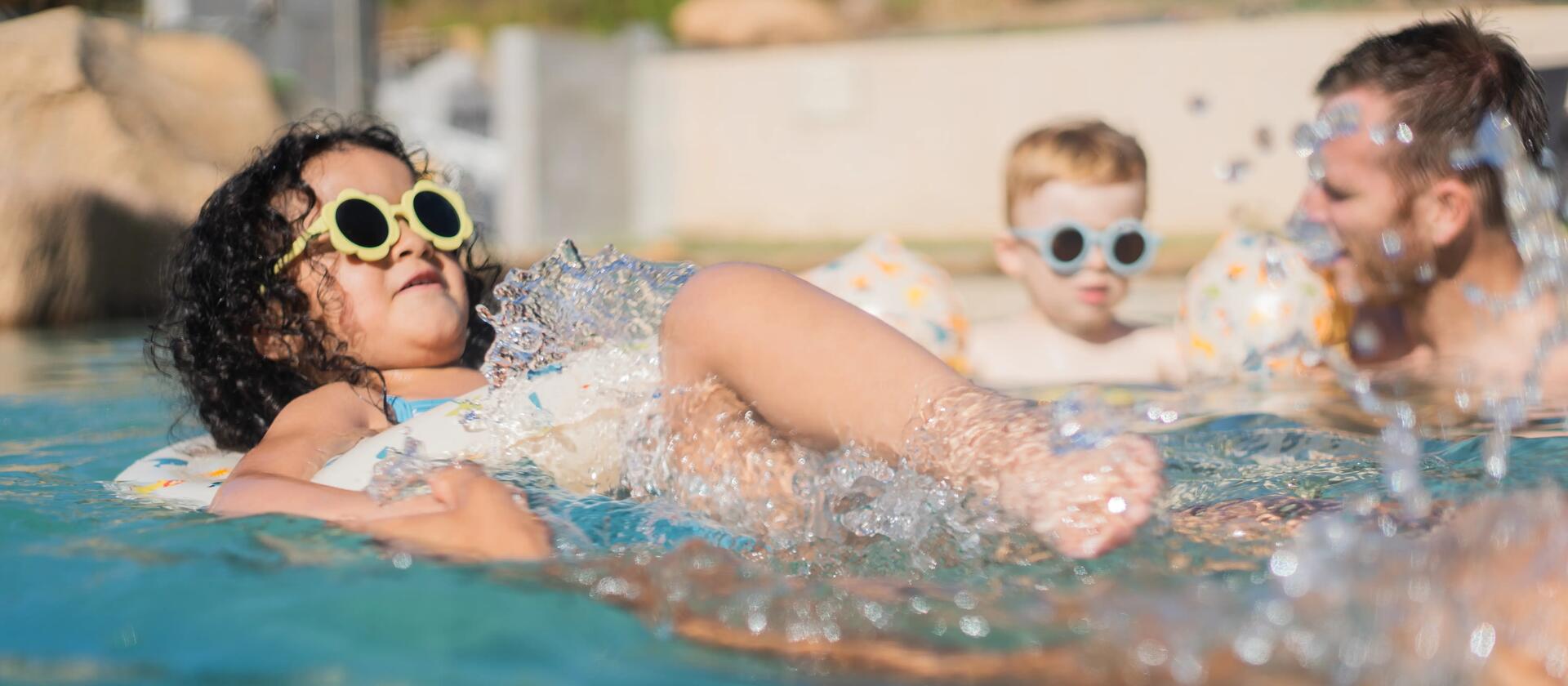 dziewczynka w okularach słonecznych pływająca w basenie 