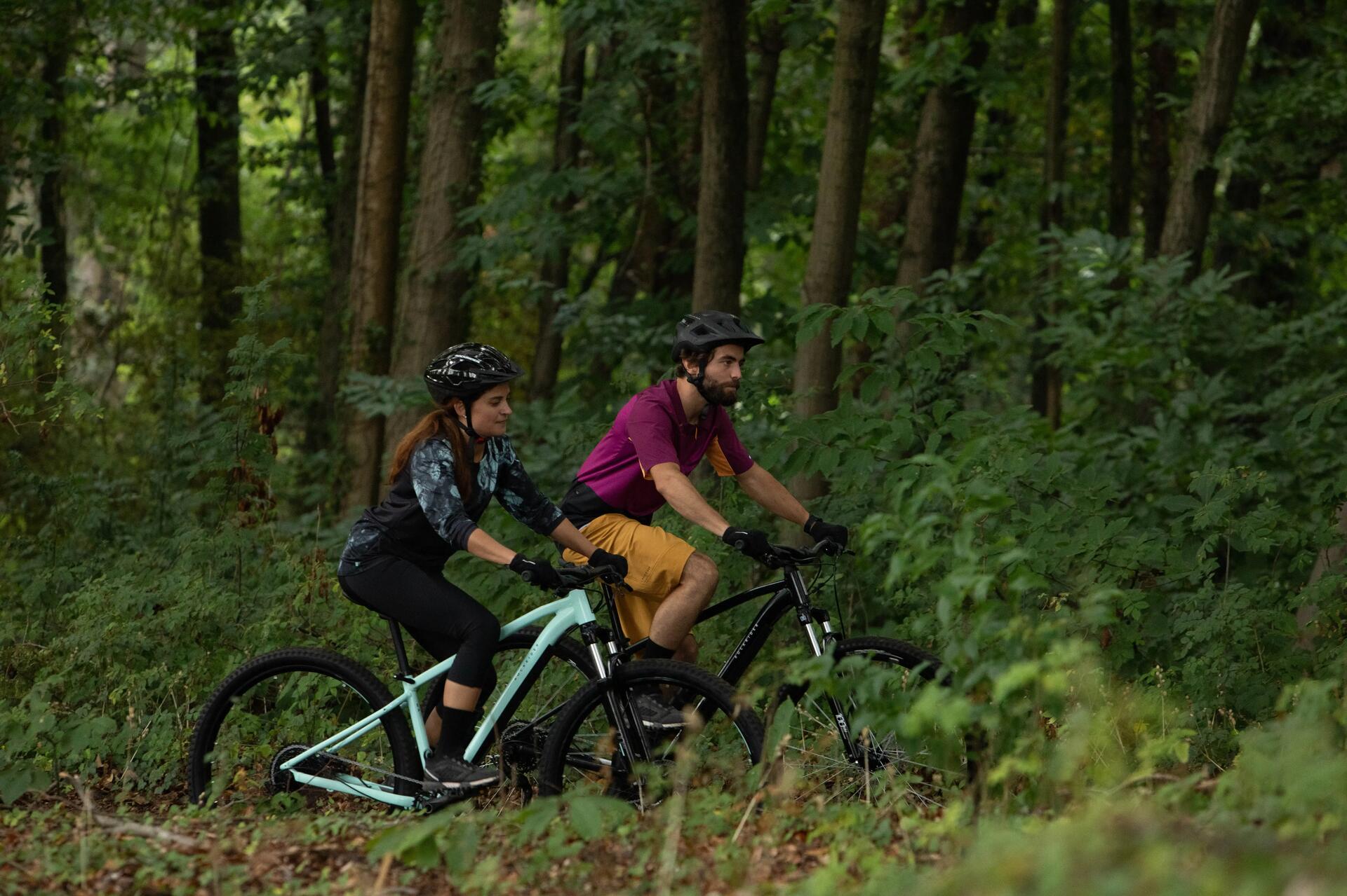 Kobieta i mężczyzna w kaskach jadący rowerami mtb po lesie