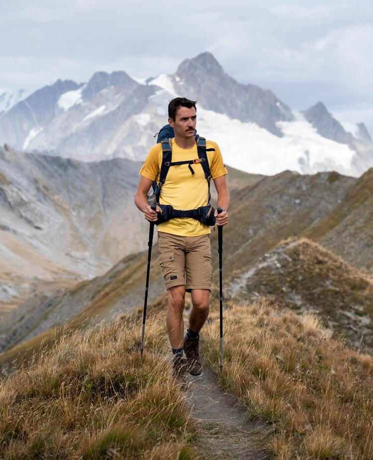 A man is hiking in the mountaings with hiking poles.