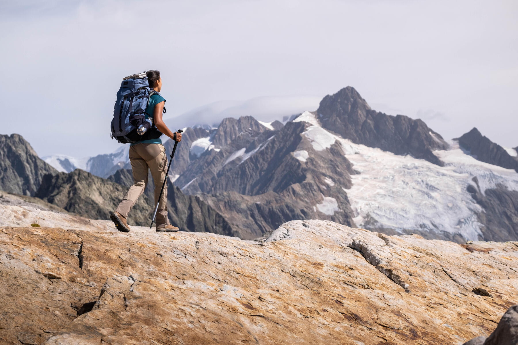 Kobieta z plecakiem i z kijkami trekkingowymi wędrująca po górach w Alpach