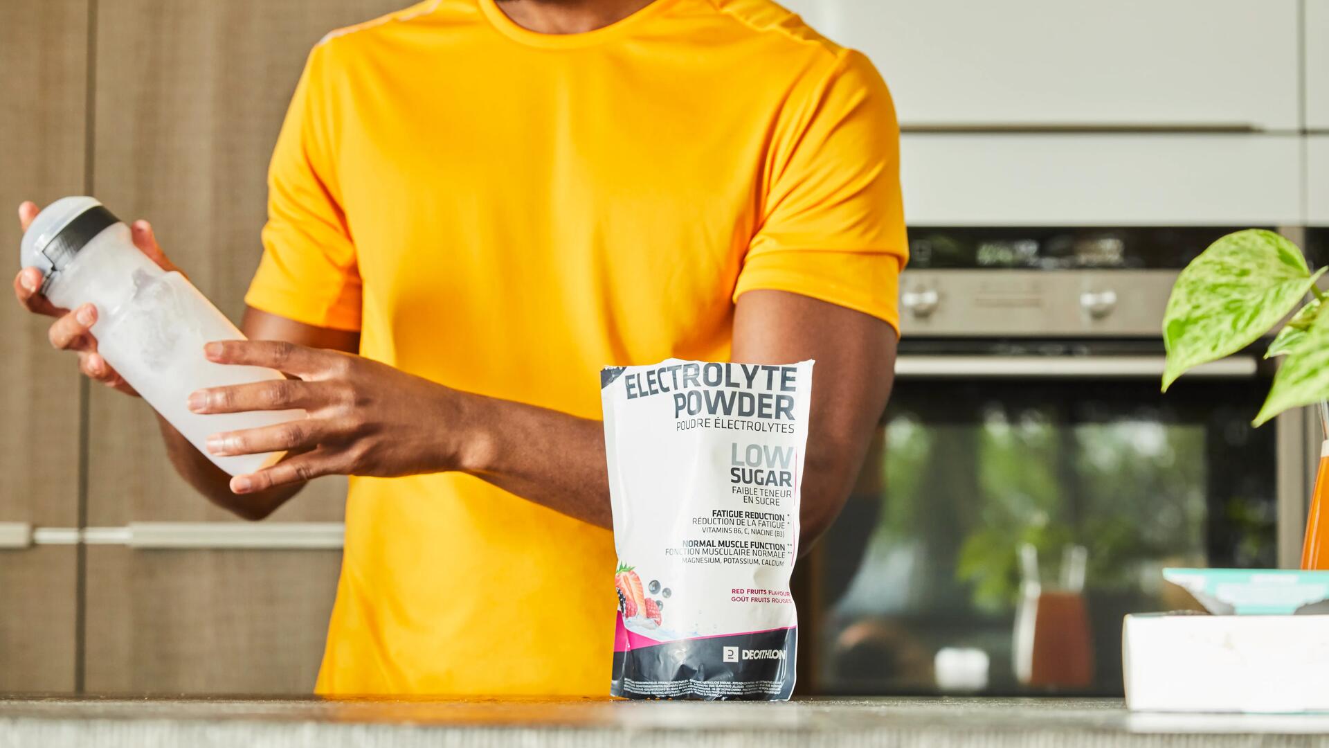 Een man maakt een elektrolytdrank van Decathlon in zijn keuken.