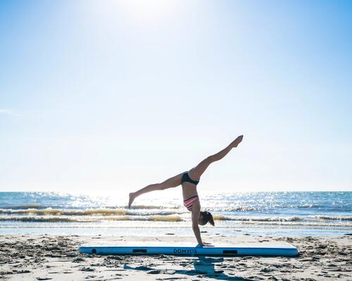 dziewczyna w stroju gimnastycznym wykonująca figurę gimnastyczną  na plaży