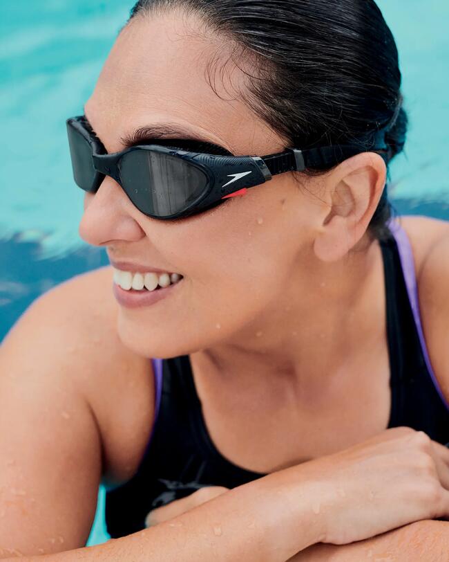 Frau im Schwimmbecken, stützt sich am Rand ab, Speedo Schwimmbrille, Speedo Badeanzug