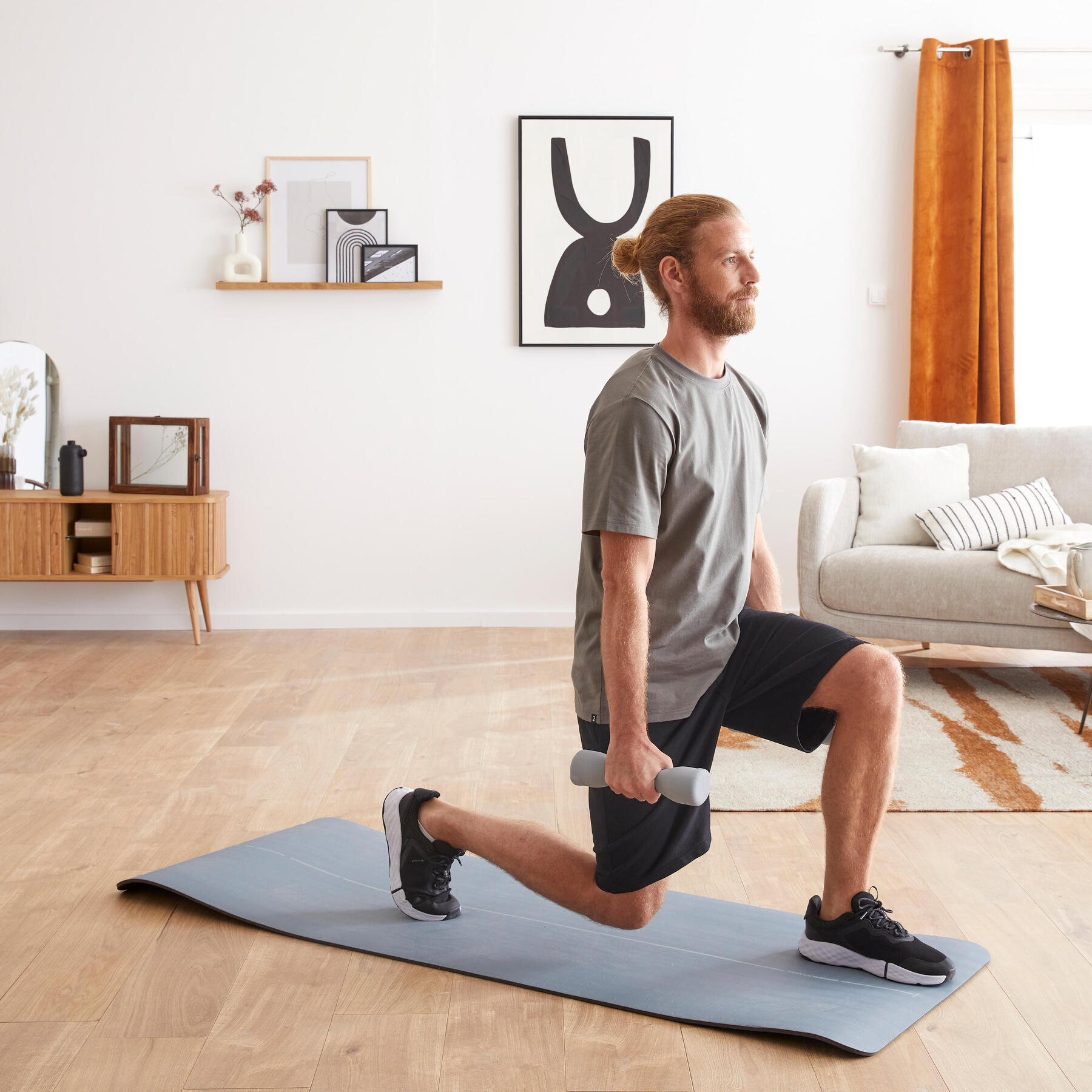 Mężczyzna w odzieży fitness wykonujący ćwiczenie na kolano biegacza przy użyciu hantli