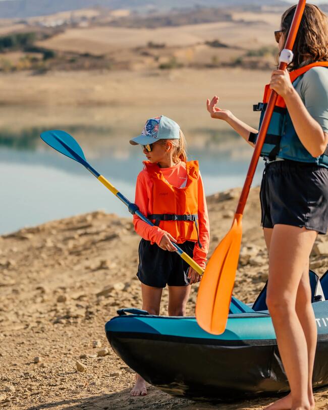 Zwei Personen in orange Schwimmwesten mit Paddeln am Seeufer, trockene Landschaft im Hintergrund.