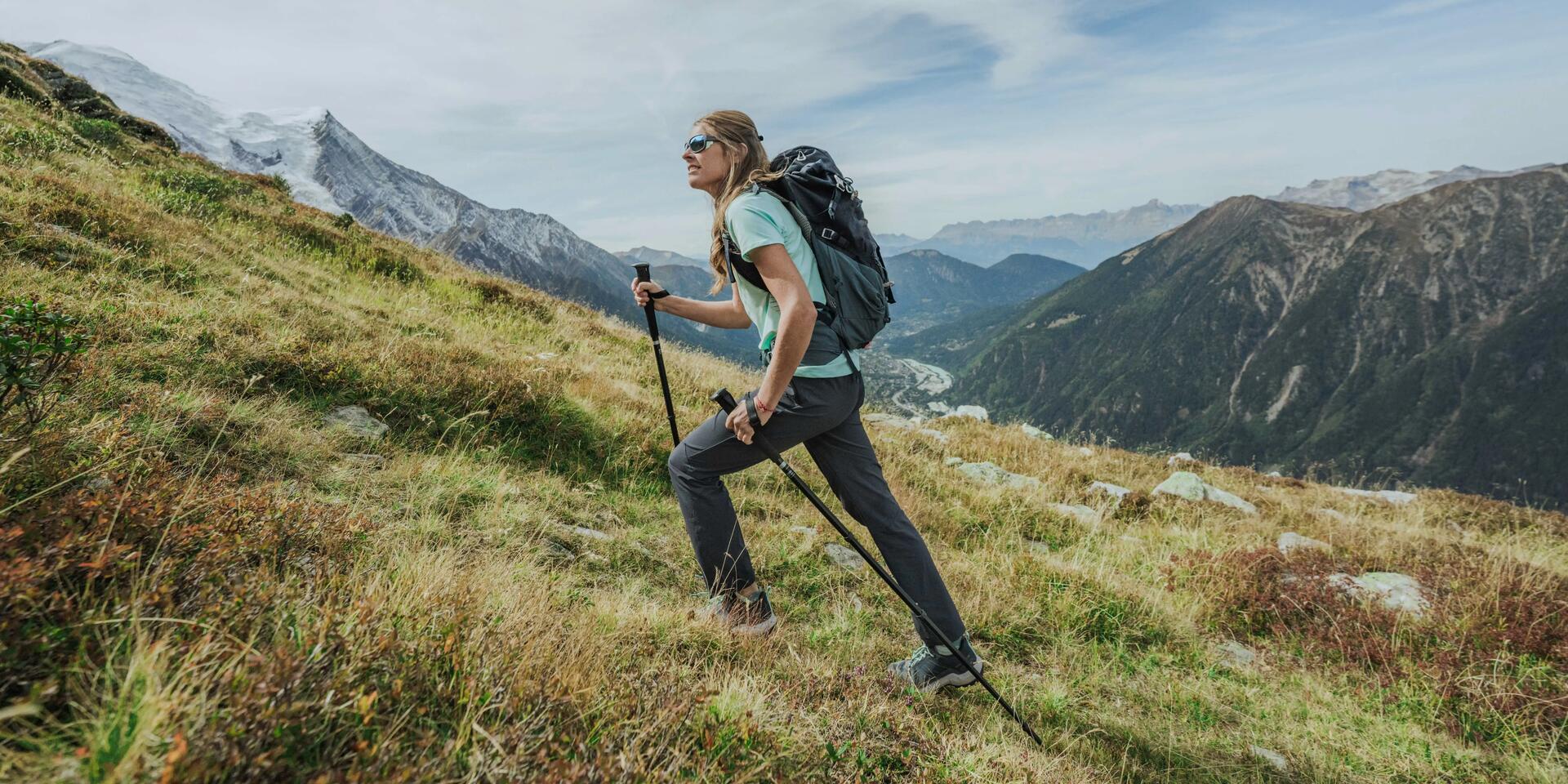 kobieta wędrująca po górach z kijkami trekkingowymi
