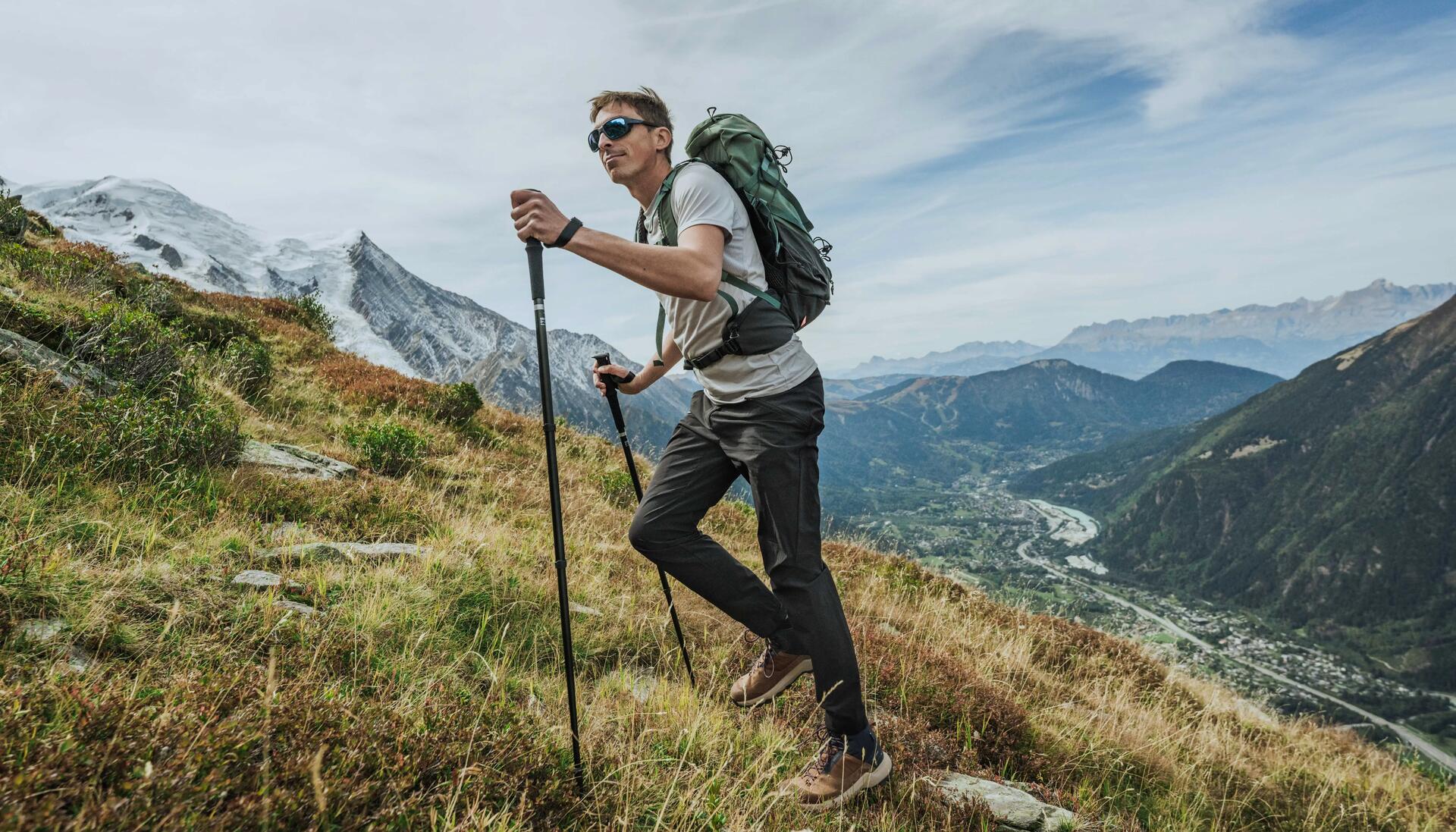 mężczyzna wędrujący po górach z plecakiem turystycznym na plecach trzymając kije trekkingowe w dłoniach