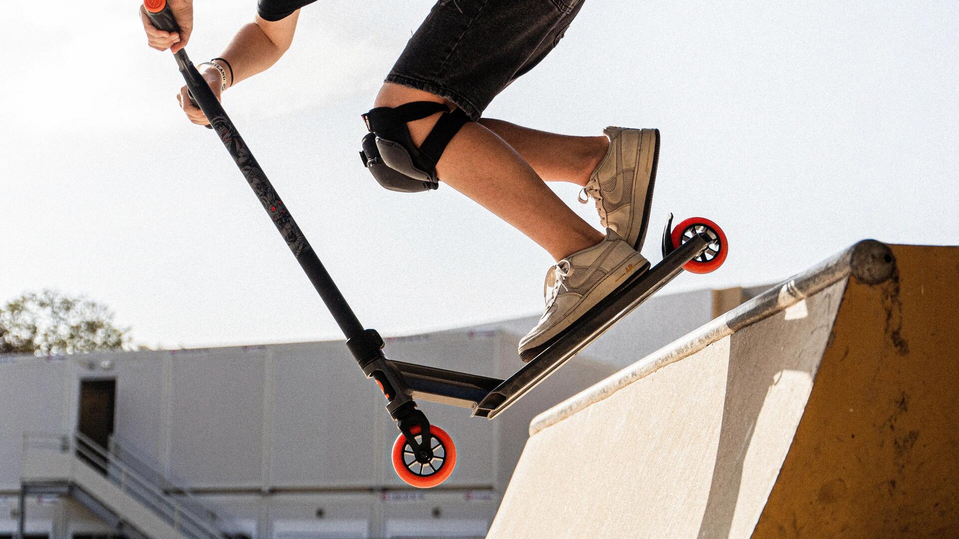 chłopak w kasku trenujący na hulajnodze wyczynowej na skateparku