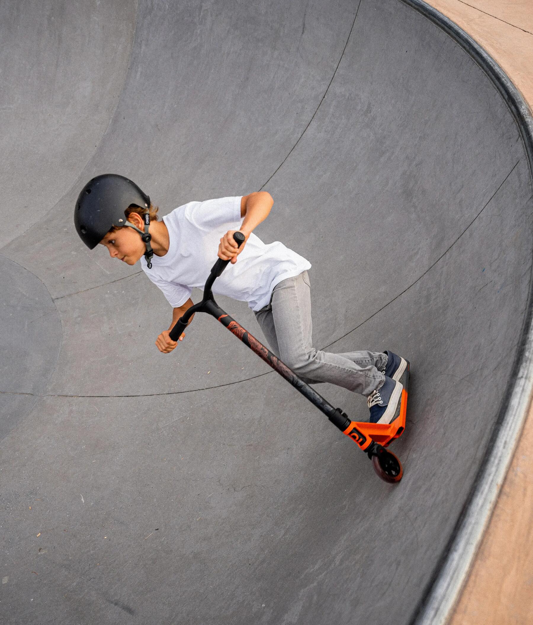 Chłopiec jeżdżący na hulajnodze wyczynowej na skateparku