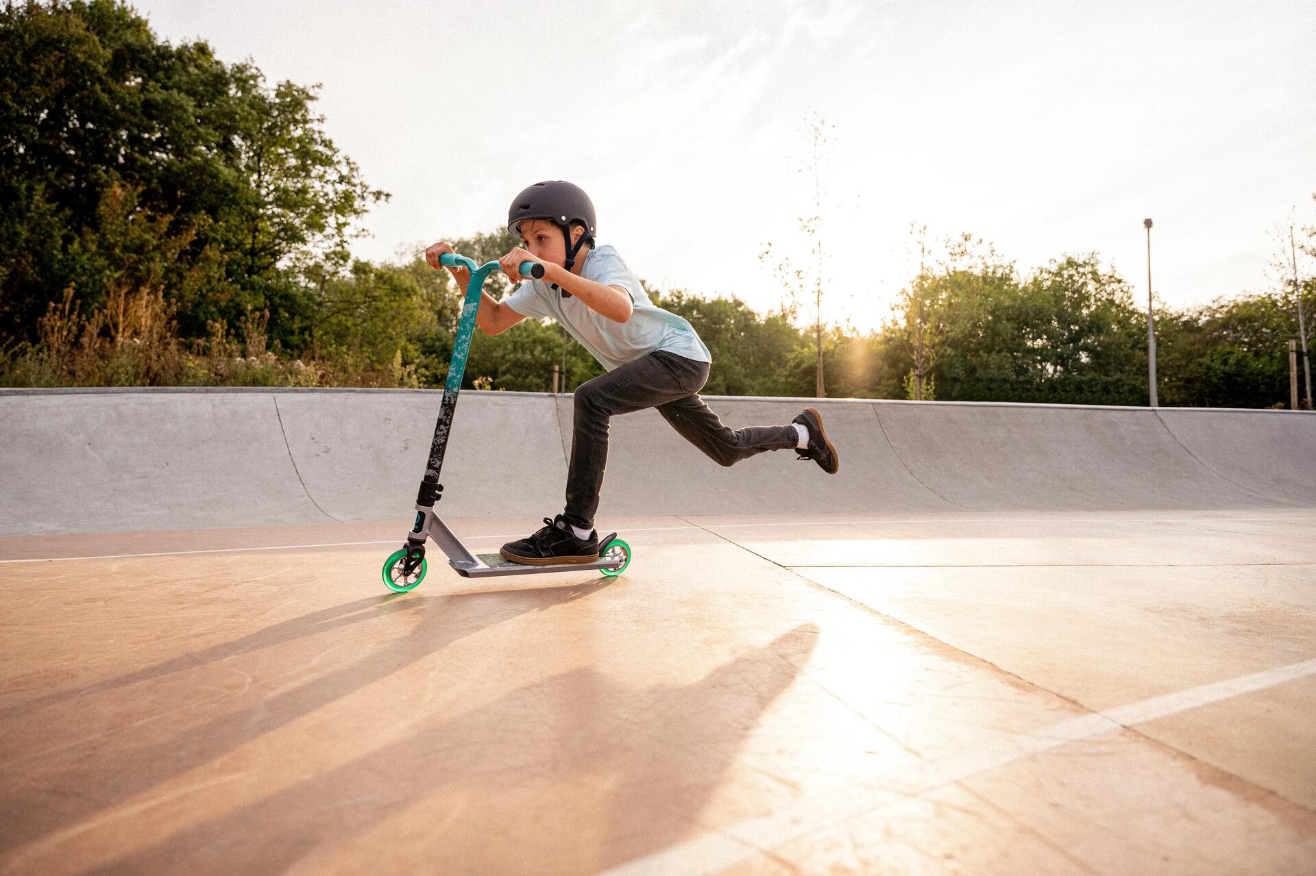 Chłopiec jeżdżący na hulajnodze wyczynowej na skateparku