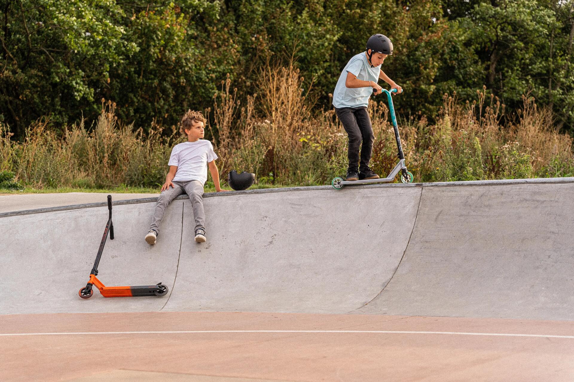 Dwóch chłopaków na hulajnogach wyczynowych na skateparku