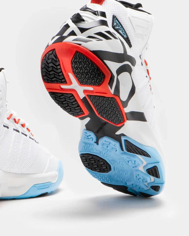 Weiße SS500 Basketballschuhe mit schwarzem, rotem und blauem Sohlenmuster, strukturierte Oberfläche, dynamische Form.