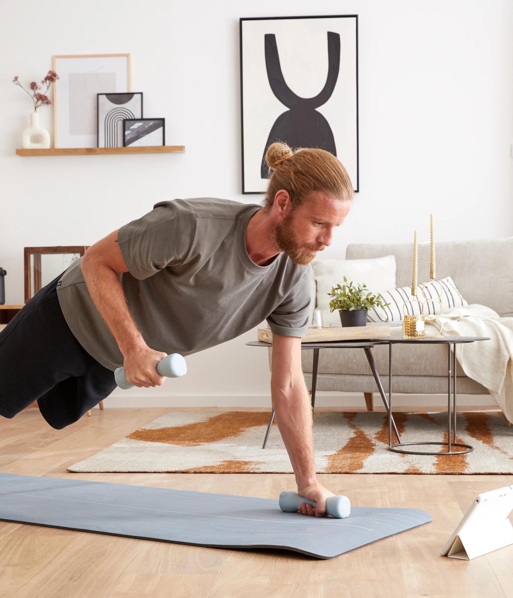 Man doing pull-ups with dumbbells on an exercise mat